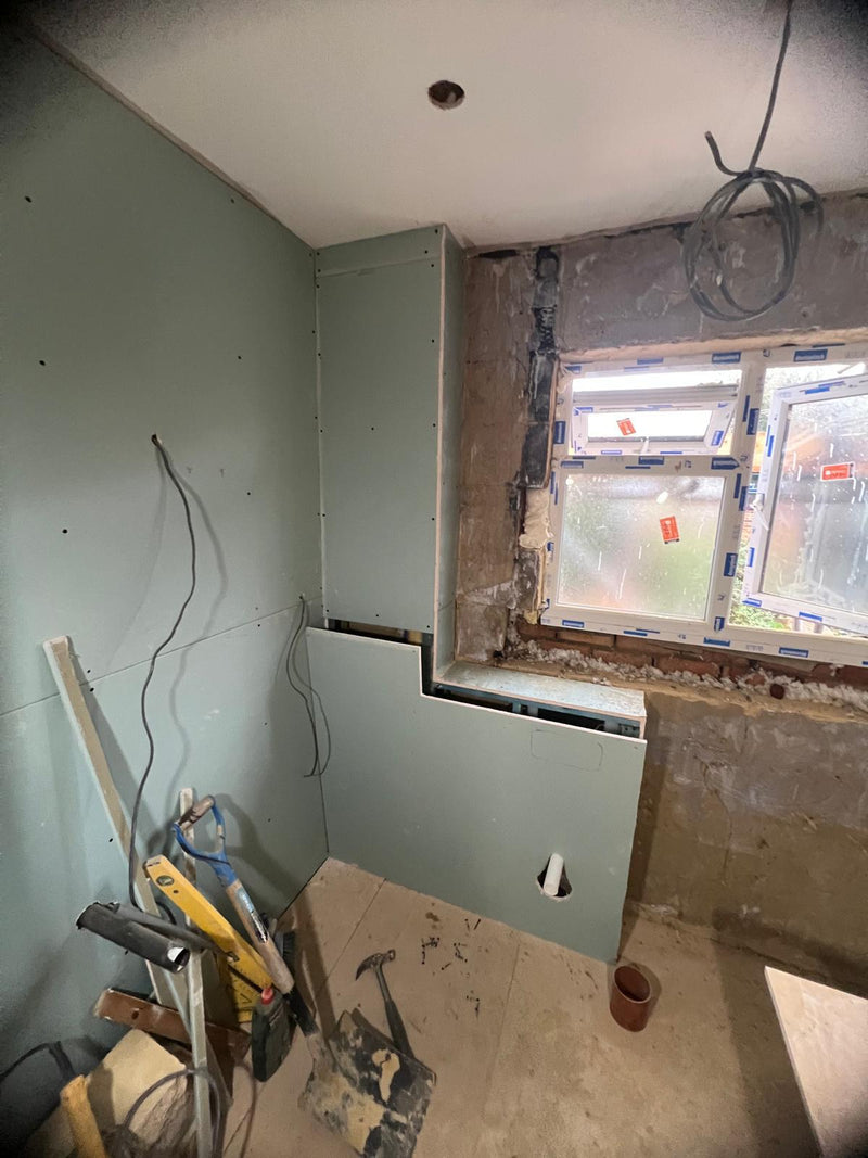 First-fix plumbing stage of a bathroom renovation featuring newly installed copper piping and a blue concealed toilet cistern frame against a bare wall.