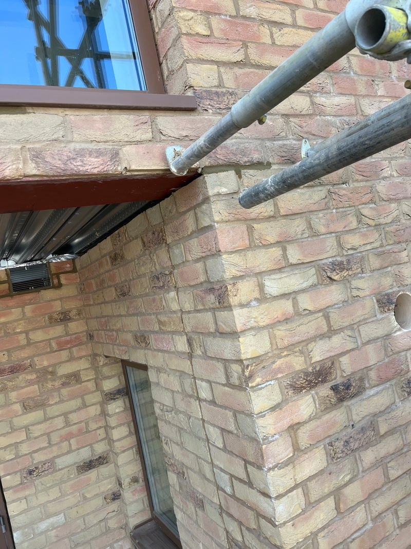 Side perspective of a cantilevered brick corner supported by a structural RSJ steel beam, showcasing precision alignment and advanced masonry engineering.