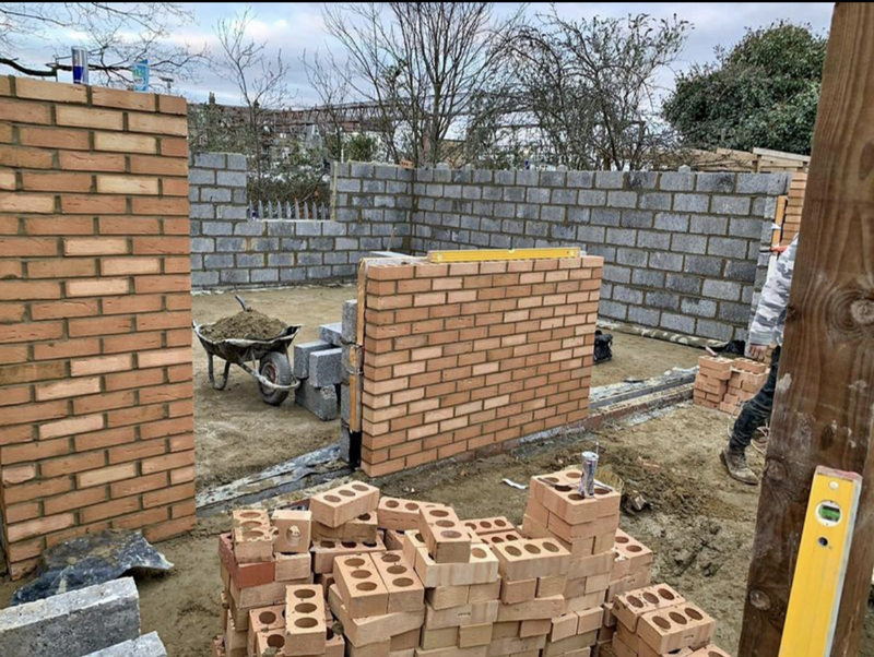 A professional brickwork project in London featuring a decorative protruding brick pattern (brick relief) on a residential facade. The image shows the skilled masonry work on a scaffolded site, highlighting Brobrick Construction's expertise in custom architectural brickwork.