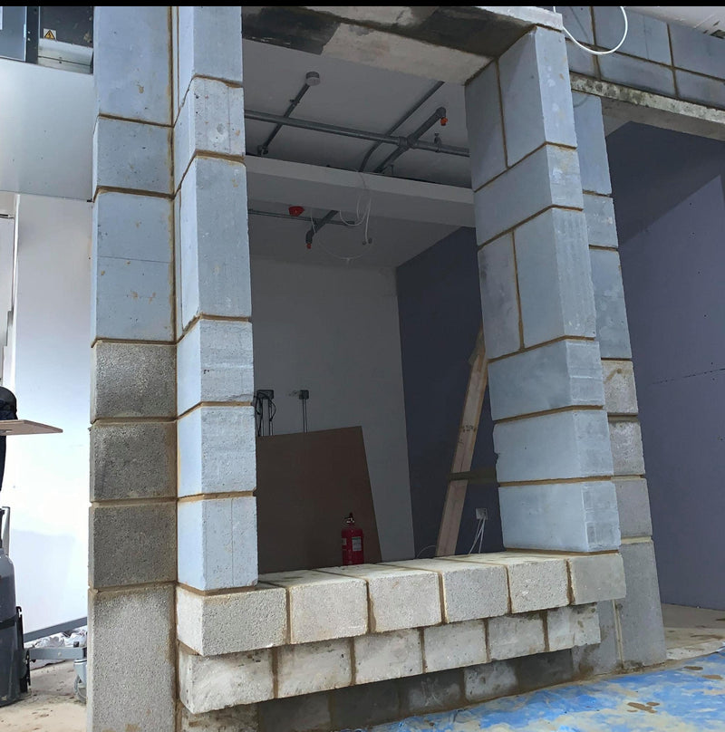 Close-up of a structural partition wall showing a precisely framed internal opening with clean breeze block masonry and square-edged reveals.