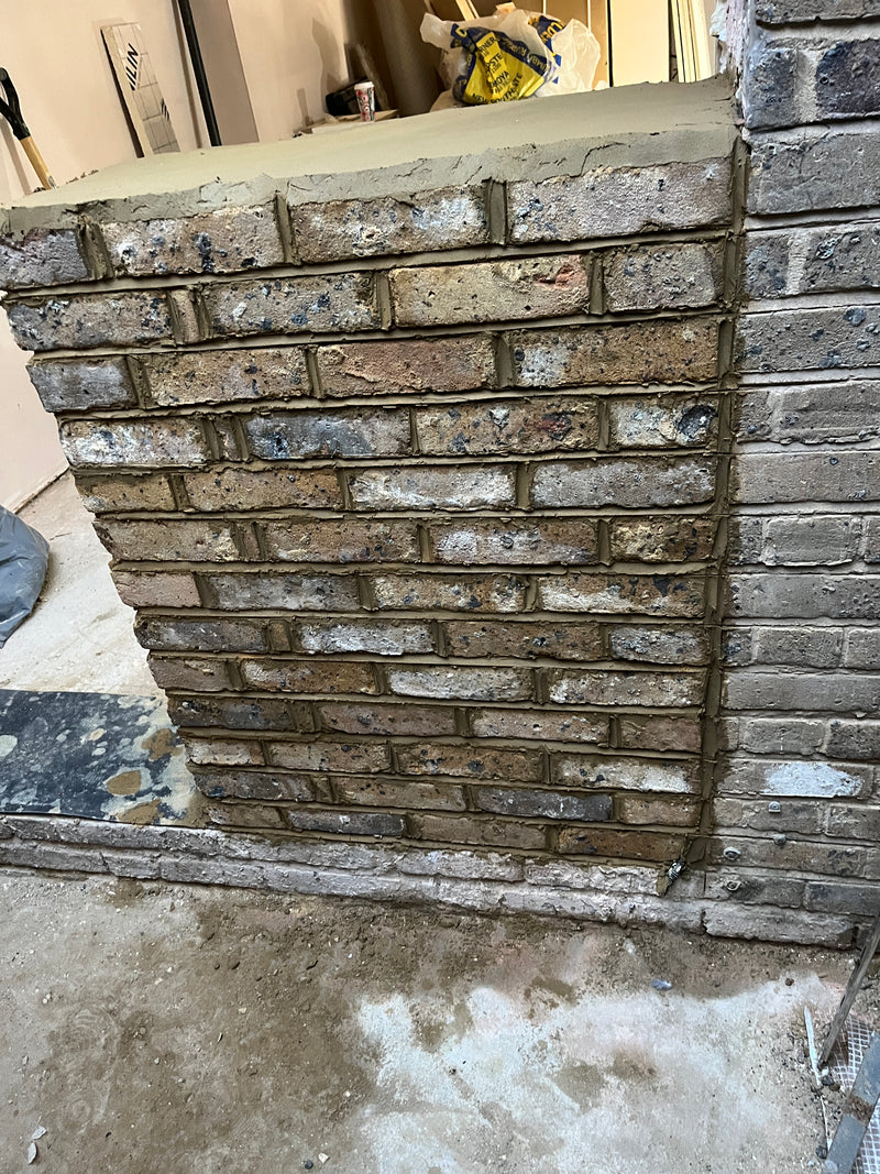 A newly constructed internal brick pier featuring reclaimed-style bricks and professional mortar bedding, providing structural support within a renovation project.