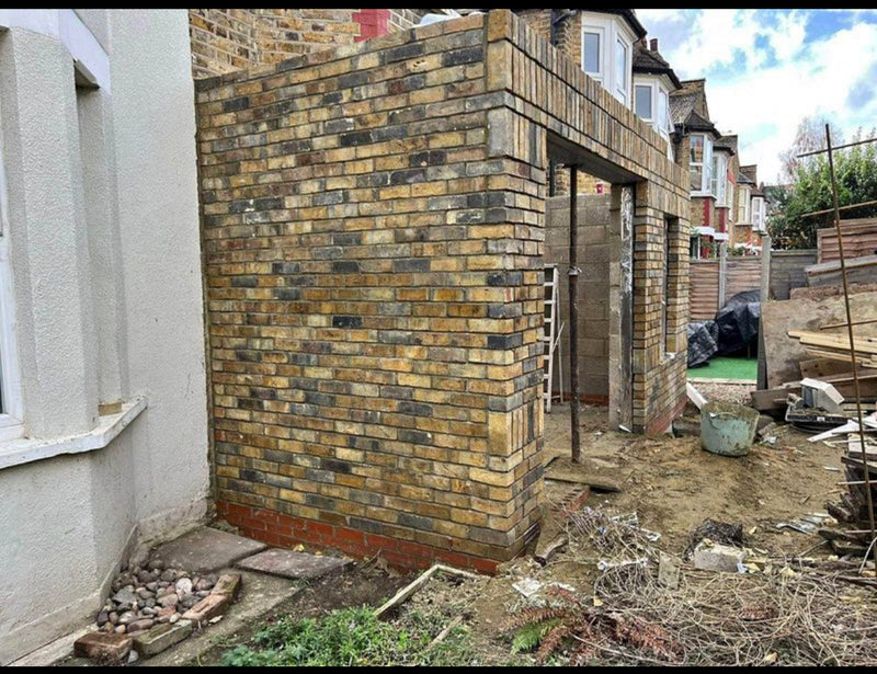 A completed house extension featuring traditional London stock brickwork and a vertical soldier course lintel over the doorway.