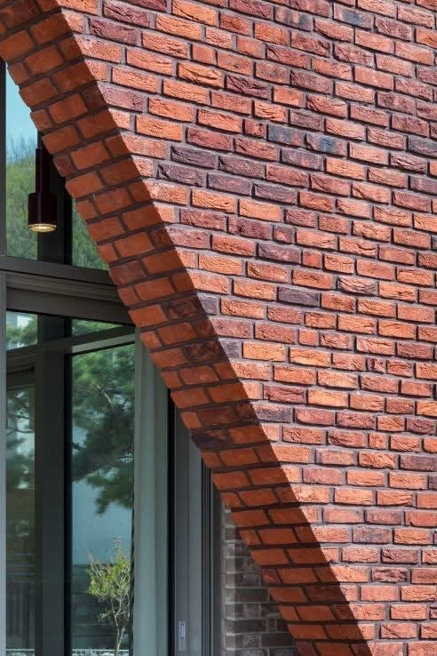 Modern bespoke brickwork featuring a sharp geometric gable line and high-precision red multi-brick alignment on a luxury London residential project.