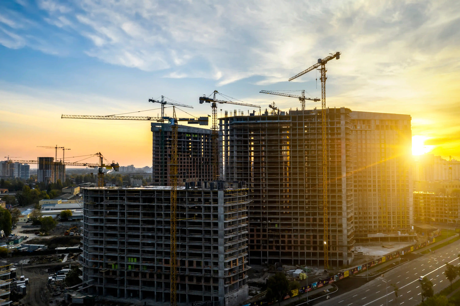 An aerial sunset view of multiple high-rise construction sites in London featuring several tower cranes and reinforced concrete building frames. This represents the scale and professional capability of London’s trusted construction specialists.