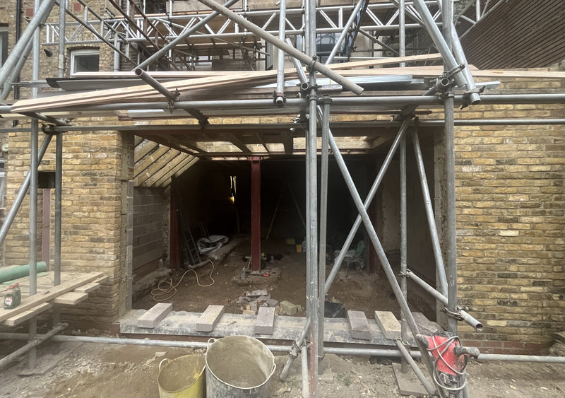 View of a red oxide structural steel RSJ beam and central support column integrated with internal blockwork and timber floor joists.