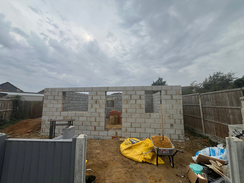 Full-scale internal blockwork shell for a large residential extension, featuring precise window and door apertures and level masonry courses.