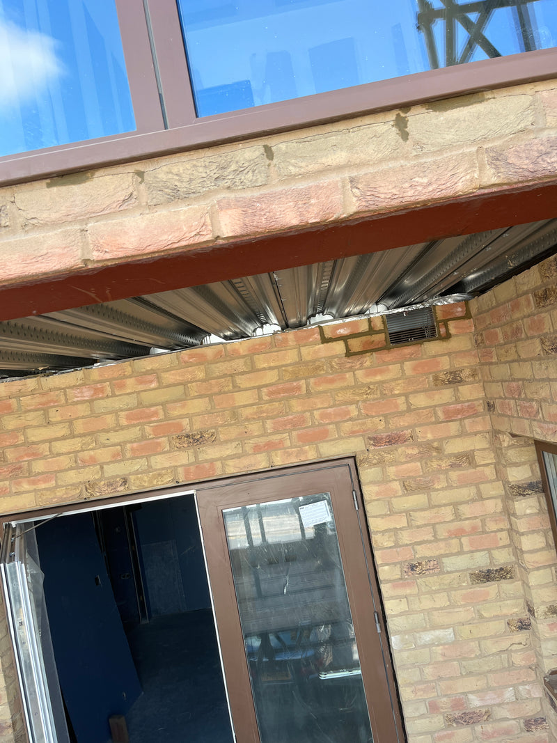 High-skill structural brickwork featuring a suspended masonry overhang with a window above, demonstrating expert support and precision alignment on a modern home extension.