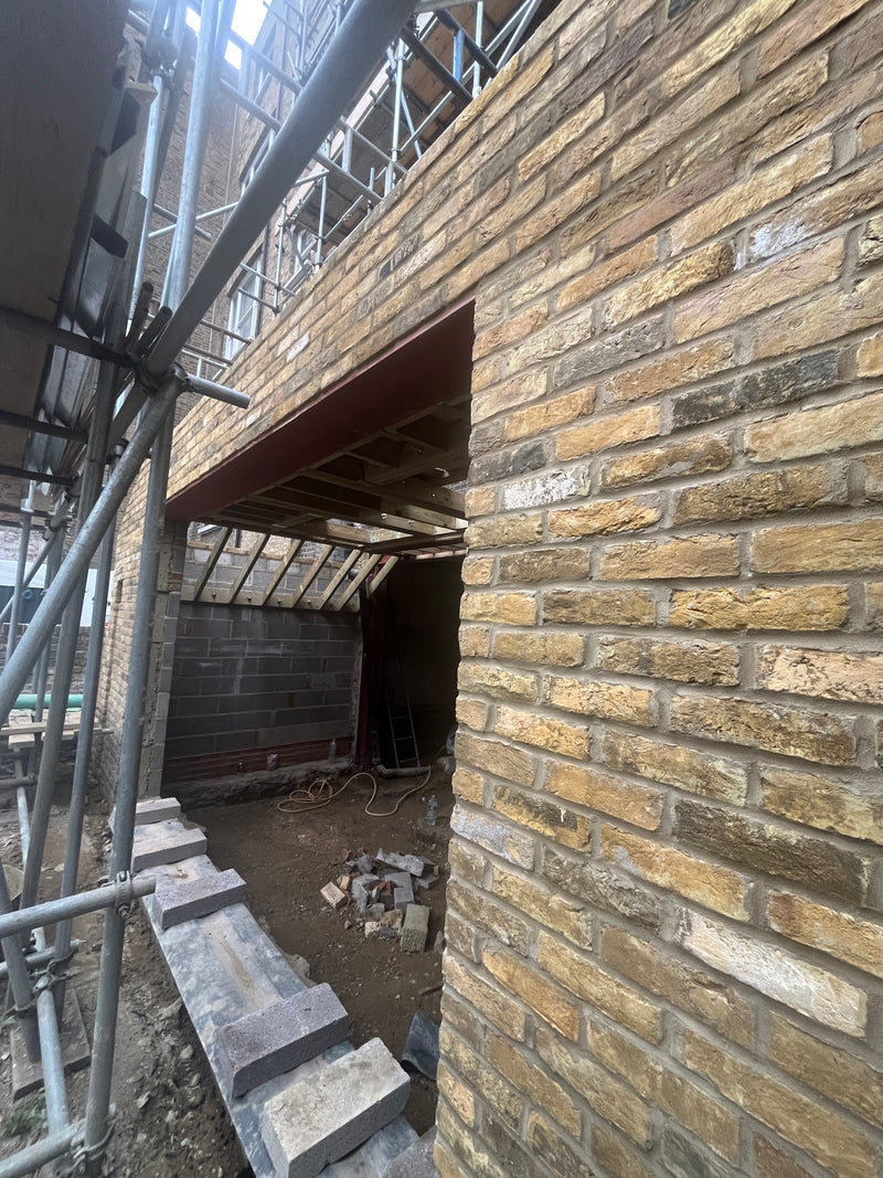 View of a heavy-duty structural steel RSJ supporting a wide-span brick elevation on a house extension, with internal timber rafters visible.